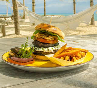 Burger with egg, crispy onions, and fresh herb garnish and a side of fries