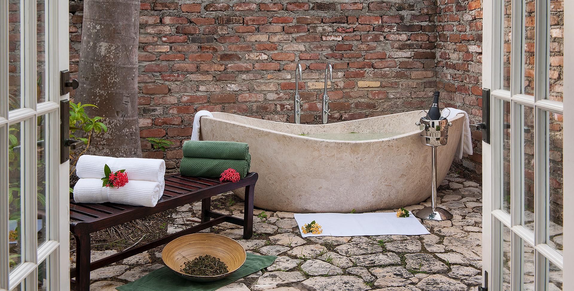 A bathtub and a table in front of a brick wall