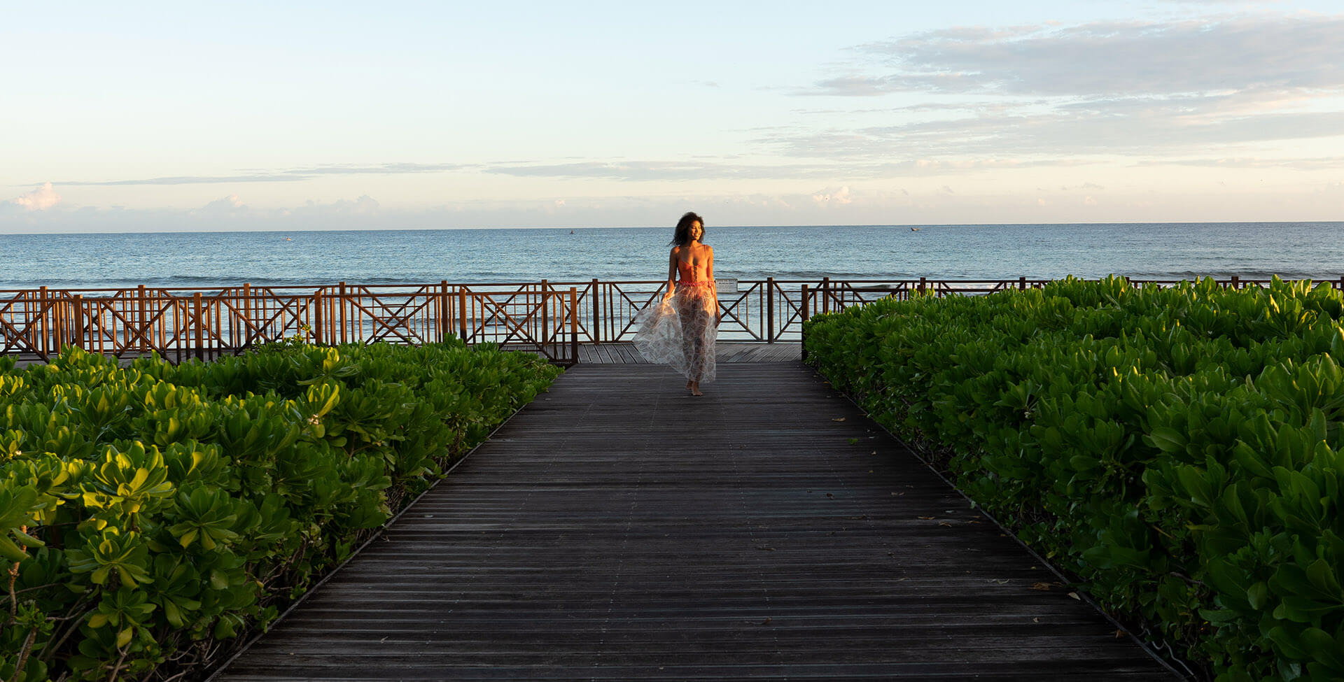 A woman walking on a wooden walkway by the water