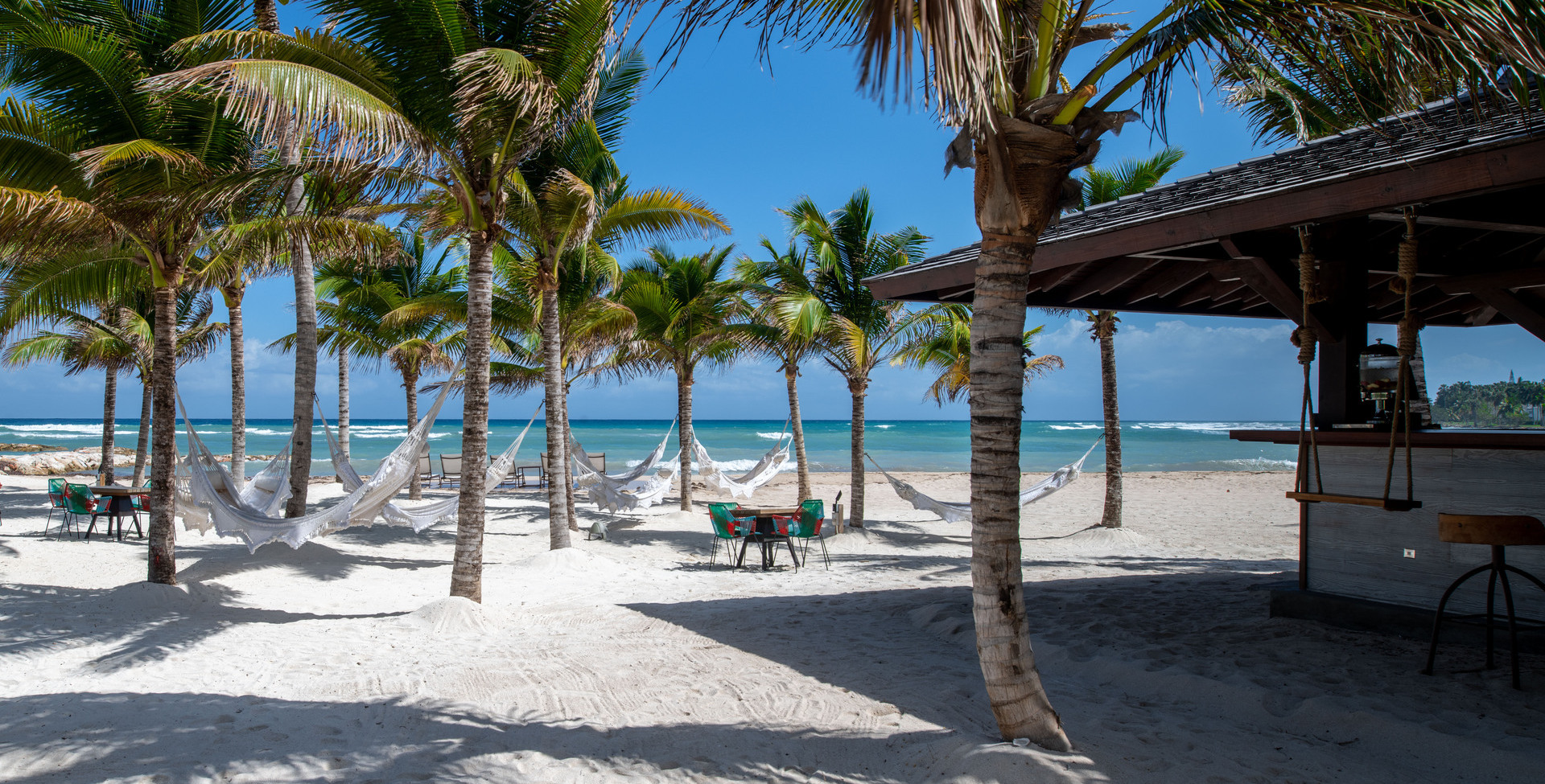 Beach bar and grill with woven hammocks hanging from palm trees on the beach