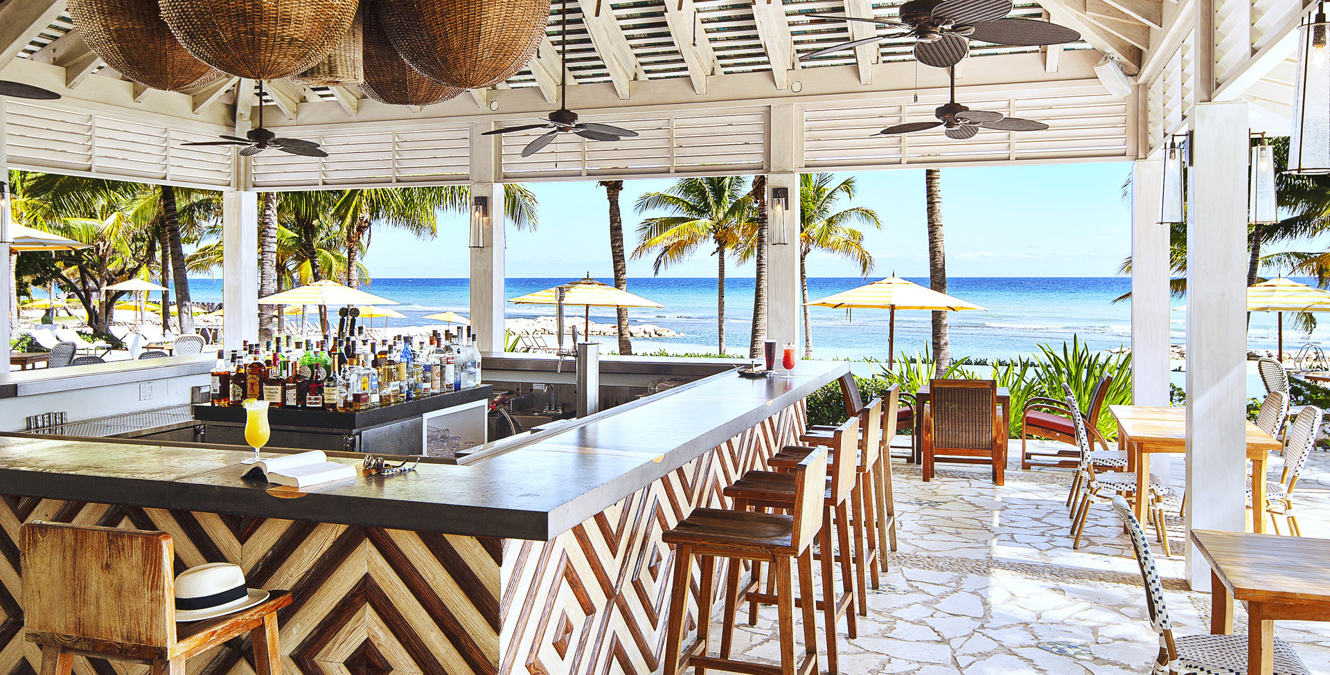 Covered bar with ceiling fans and a beach view