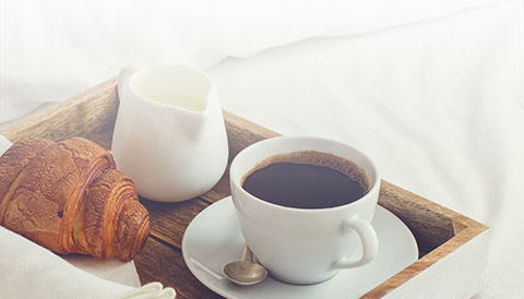 a tray with a cup of coffee and croissants